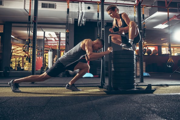 athletic-man-and-woman-with-a-dumbbells-training-and-practicing-in-gym